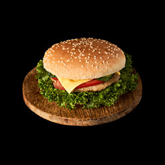Delicious classic burger on wooden cutting board isolated on black background