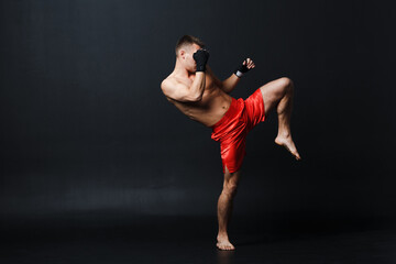 Sportsman muay thai man boxer stance ad knee kick at black background