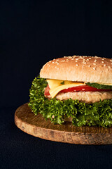 Delicious classic burger on wooden cutting board isolated on black background