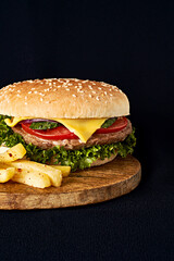 Delicious classic burger on wooden cutting board isolated on black background