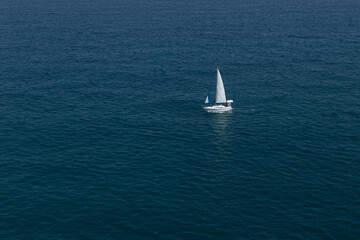 Elegant yacht sailing in still water of an open Mediterranean sea on a clear day. Idyllic seascape. Summer vacations, leisure activity, sport and recreation.