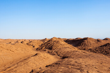 Lut desert in Iran. Sandy and rocky dunes in the Iranian desert with blue sky. Beautiful cover or background image.