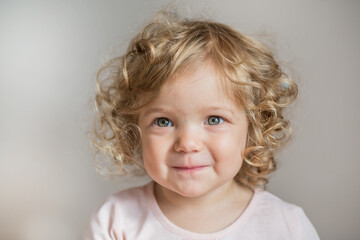 Naklejka premium Curly beautiful baby girl in white dress on light gray background 