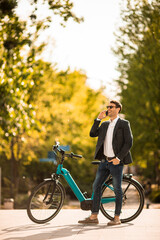 Obraz premium Young businessman on the ebike using mobile phone