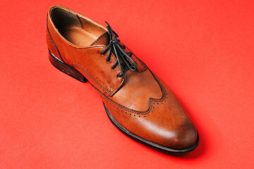 Mens shoes. Brown leather shoes isolated on a red background. Boots made of genuine leather...