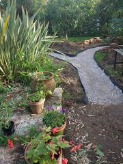 Landscape of garden design project building constructing a winding path with antique recycled house bricks, shape cut in grass ground and hard core base, edging laid before sand stone laying in Autumn