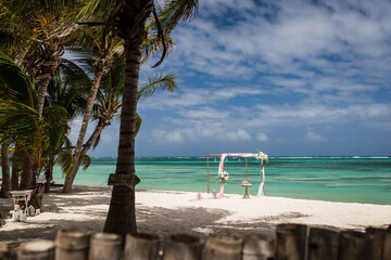 Wedding bamboo gazebo, decorated with tropical flowers and coloured fabrics on the paradise beach with palm trees, white sand and blue water of Caribbean Sea, Punta Cana, Dominican Republic