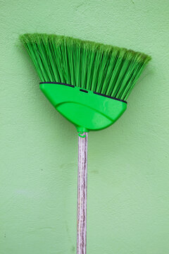 Vassoura verde com cabo de madeira sobre o fundo verde