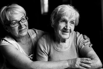 Old woman with her adult daughter. Black and white photography.