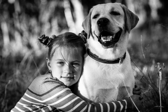 Little girl and her dog, outdoors. Black and white photo.