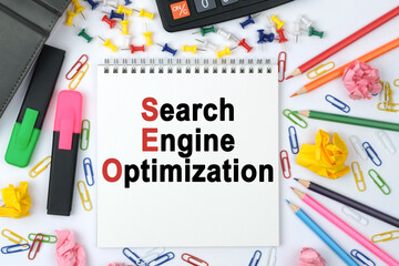 On the table is a calculator, diary, markers, pencils and a notebook with the inscription - Search Engine Optimization