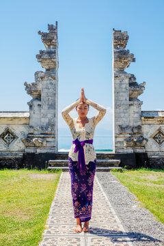 Portrait of young woman in traditional clothing with eyes closed standing outside Pura Candidasa temple