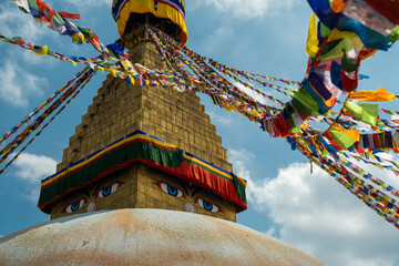 Multicolored Buddhist prayer flags with mantras on a background of blue sky and an ancient stupa. Traditional Tibetan and Nepalese threads with rectangular colored pieces of fabric.