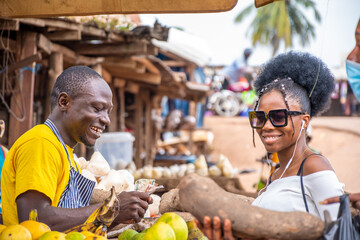 young black man selling to a woman in a local african market