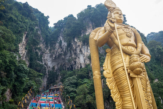 The tall golden Hindu statue of Murugan in front of the 272 steps to the Batu Caves with temples and shrines, near Kuala Lumpur, Malaysia