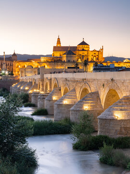 The Roman Bridge (Puente Romano) and The Great Mosque of Cordoba lit up during evening sunset, Cordoba, Andalusia, Spain
