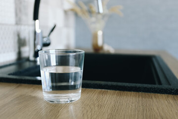 Glass of fresh cold water on table in kitchen