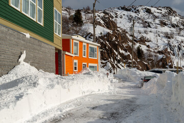 Colorful wooden houses with windows on a hill covered in fresh white snow. The buildings are green...