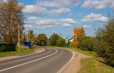 Fototapeta premium Winding asphalt rural road on an autumn day