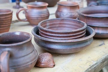 traditional dishes set of clay plates, mugs stand on a wooden table
