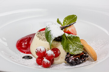 Panakota with berry sauce and fresh Strawberries, blackberries and red currants is on a plate