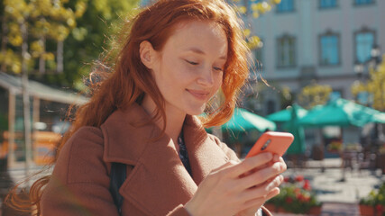 Attractive cheerful young ginger girl student using smartphone typing fast finger on screen looking very funny. For animation. User interface. Internet addiction. Digital nomad.