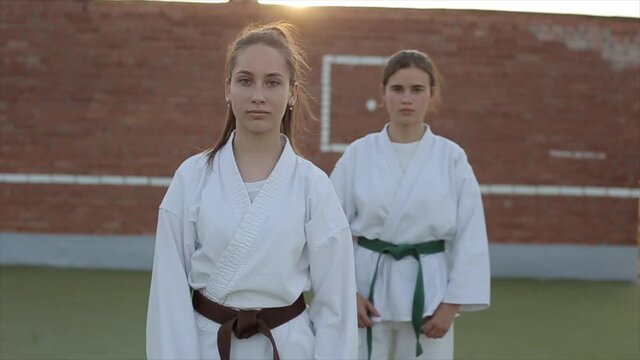 Two young women demonstrate kyokushinkai techniques in karate training on the sports ground. Front view. Close-up. Slow motion