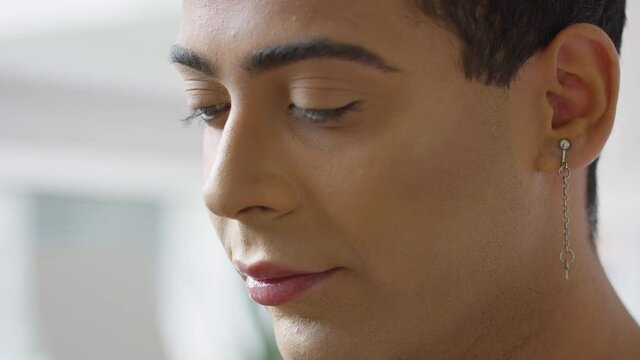 Close up portrait of young androgynous male in make up looking sad with a lot on his mind