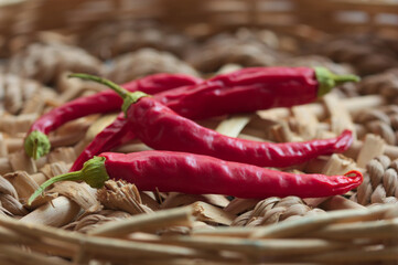 Some red chilli peppers on a wicker surface