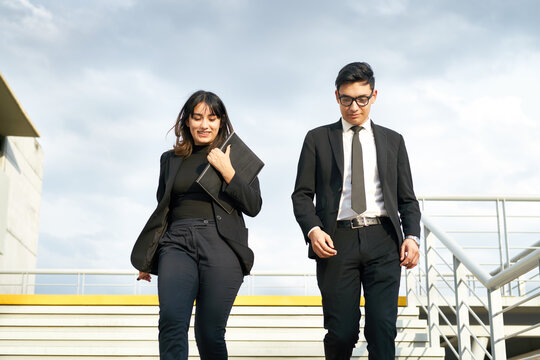 Two Smiling Businesspersons Walking Down Stairs