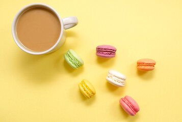 Obraz na płótnie Canvas Set of colorful macaroons and coffee. Pastries, pastries and a cup of coffee with milk on a yellow background. Confectionery. good morning. Copy space. view from above.