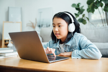 Cute teenager girl using laptop with headphones