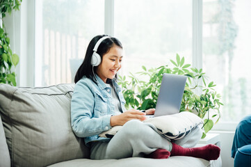 Cute teenager girl using laptop with headphones