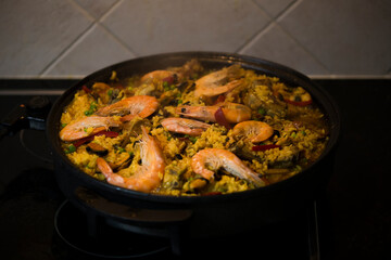 Obraz na płótnie Canvas Paella traditional Spanish food. Paella with with mussels, king prawns, langoustine and squids. Person cooking paella.Family dinner. 