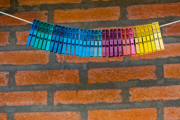 broches de colores colgados en una soga sobre pared de ladrillos