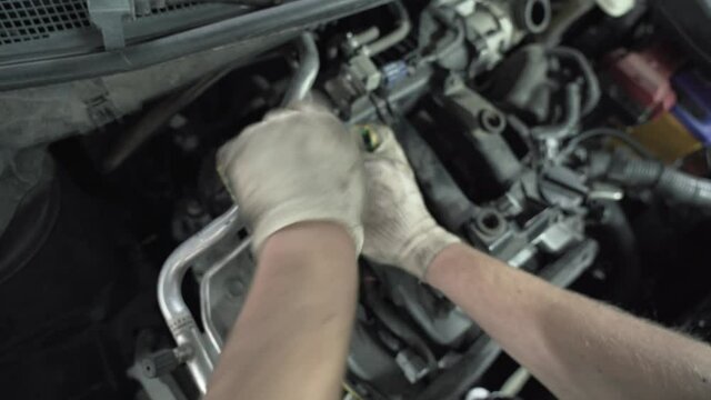 Worker hands changes spark plugs in car engine in auto service, close up.
