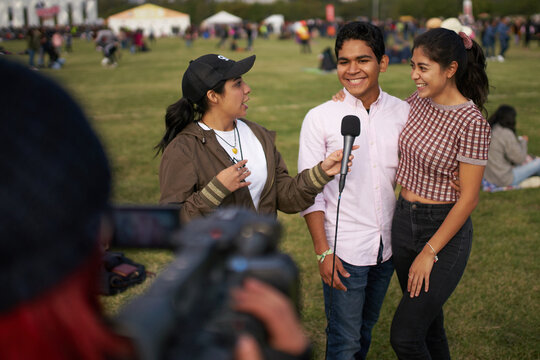 Journalist and blogger interviews a happy young couple in front of the camera at a festival