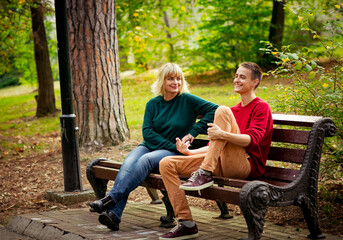 Fototapeta premium Beautiful woman,blonde,middle-aged,with her son,sitting on a bench and talking