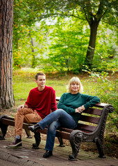Fototapeta premium Beautiful woman,blonde,middle-aged,with her son,sitting on a bench and talking