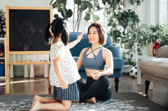 Asian young mom and daughter practicing yoga at home