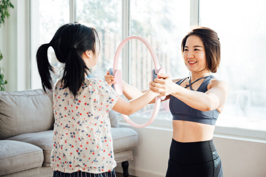 Asian young mom and daughter practicing yoga at home