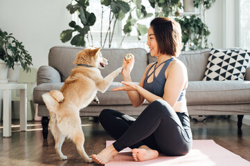 Young asian woman practicing yoga at home with pet dog