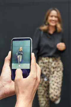 Cell phone photographer having a photo shoot with a happy and young attractive influencer woman