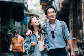 Young asian couple traveling in a city downtown and enjoying street food
