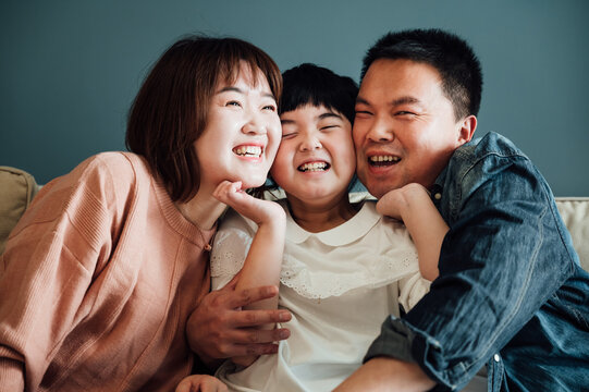 Portrait of an asian family, young parents and their daughter laughing at home