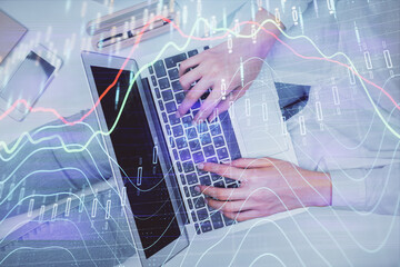 Double exposure of woman hands working on computer and forex graph hologram drawing. Top View. Financial analysis concept.