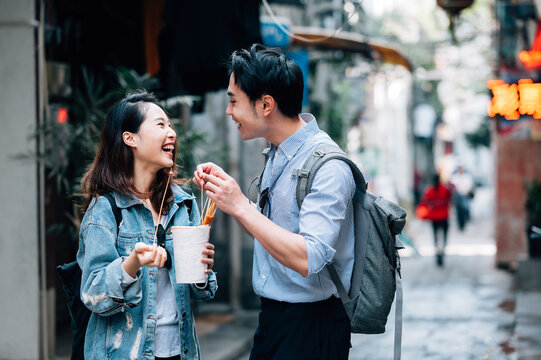 Young asian couple traveling in a city downtown and enjoying street food