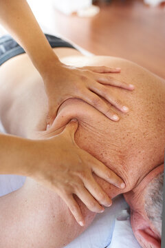 Masseuse giving a firm massage to a senior man
