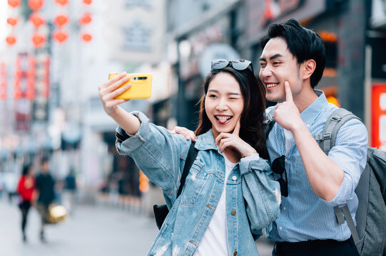 Young asian couple traveling in a city downtown and using cellphone