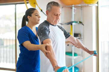 Senior man at a rehab clinic receiving exercise instructions from trainer